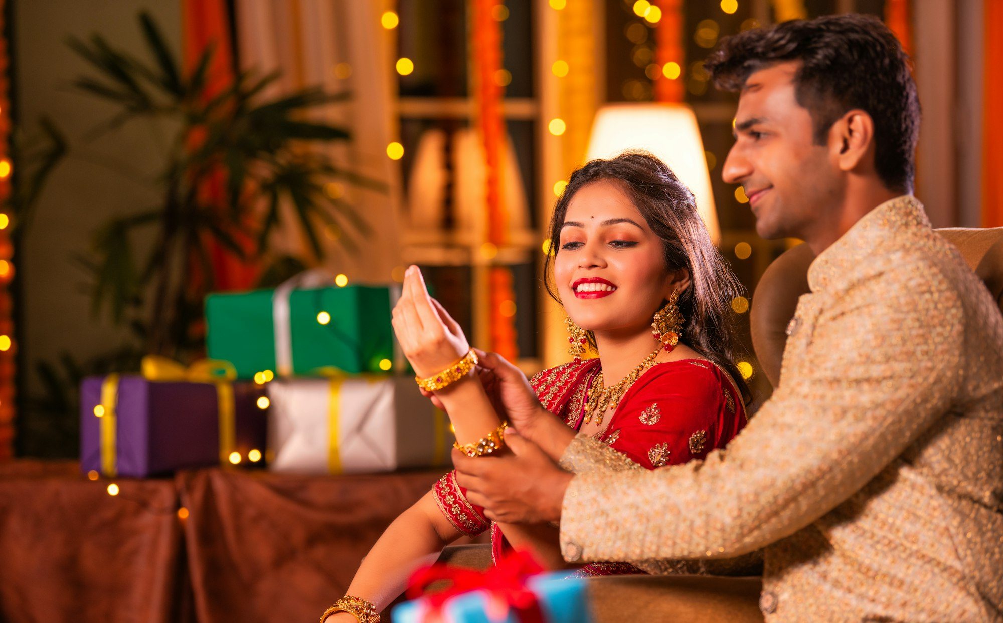 Indian husband puts gold bangle or bracelet in wife's wrist on diwali festival or anniversary